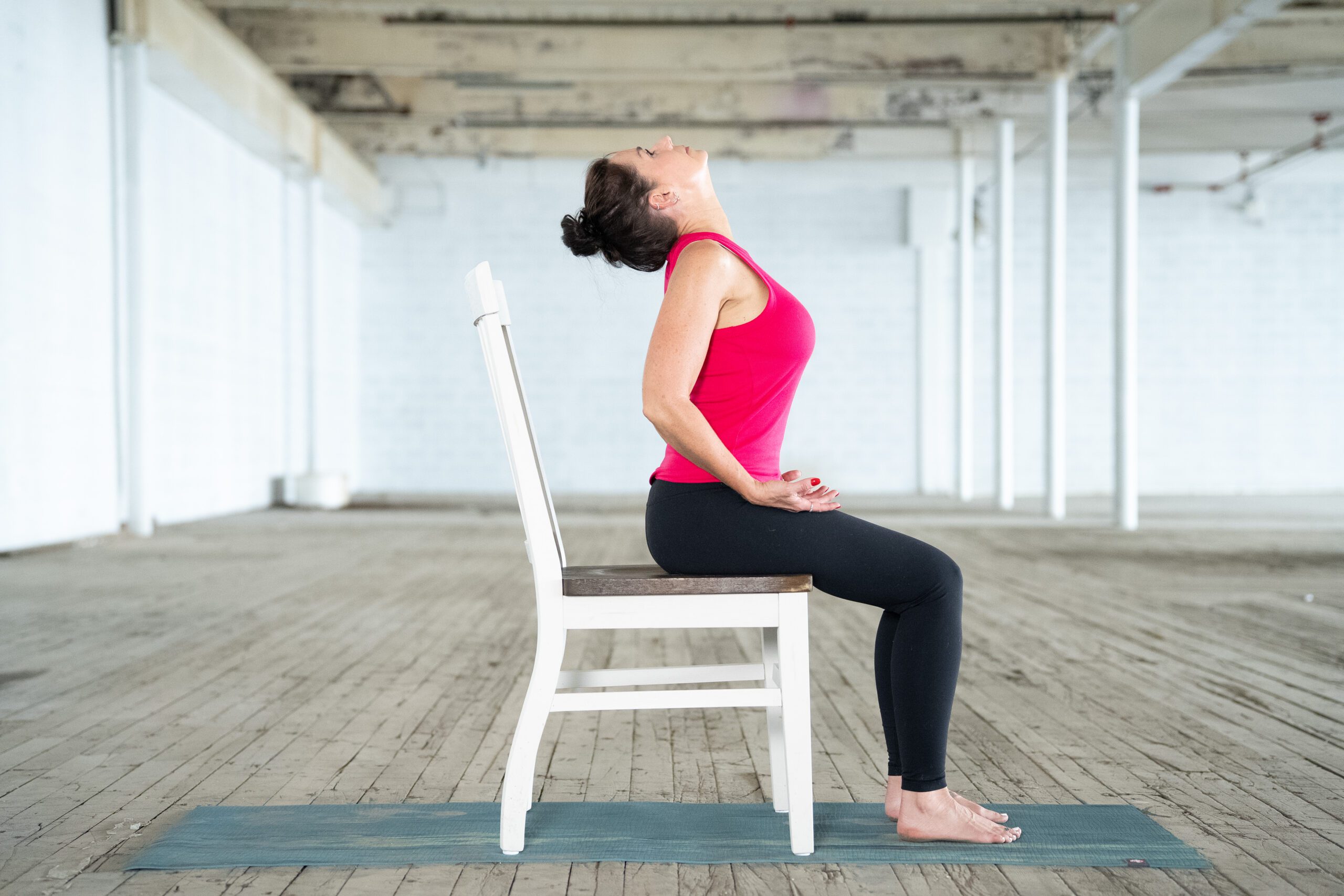 sitting in a chair, adaptive yoga instructor jane hart demostrates a cat cow stretch