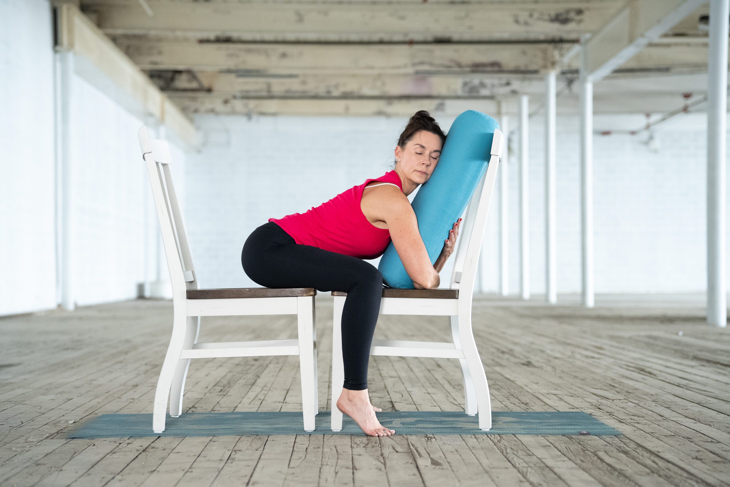 jane hart demonstrates a modified yoga pose using two chairs and a bolster