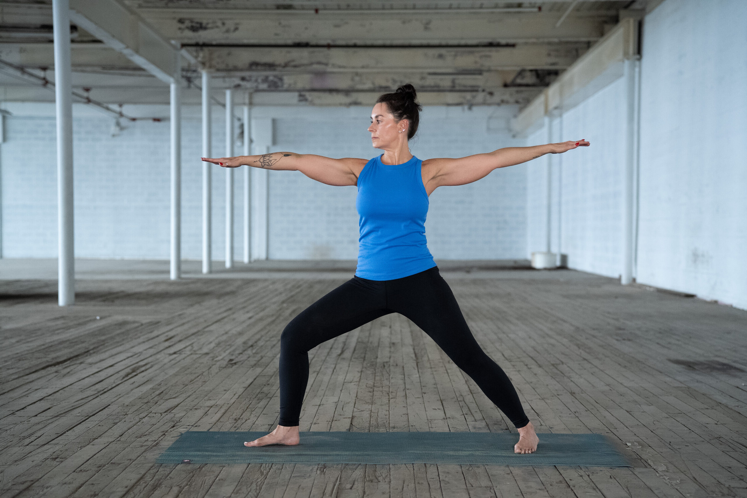 Yoga teacher jane does a warrior pose in a warehouse space in greenville sc