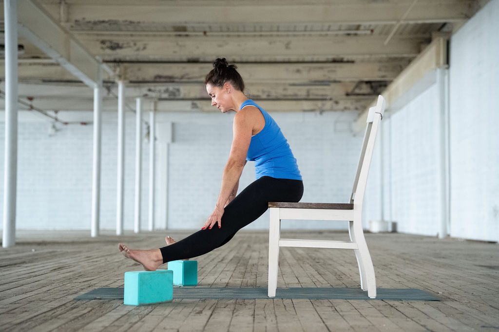 Jane Hart, adaptive yoga instructor showcases a modified yoga pose using a chair and two yoga blocks