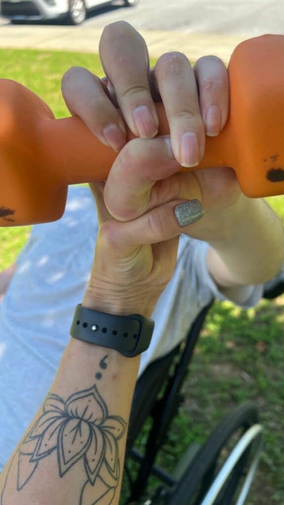 modified ability yoga instructor jane hart helps a client work on his grip with an orange weight during a 1:1 private yoga for disabilities session