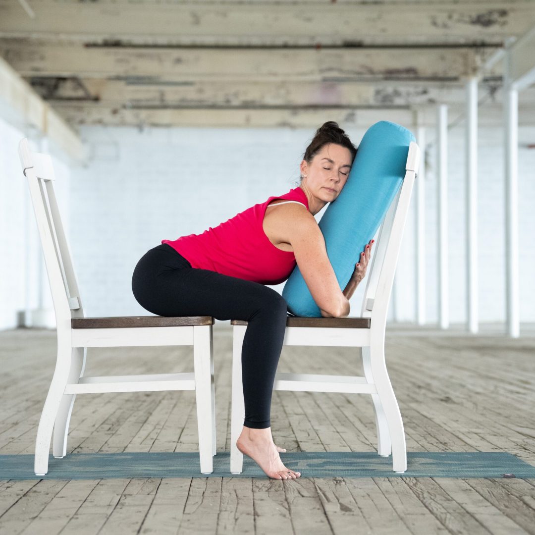 jane hart demonstrates a modified yoga pose using two chairs and a bolster