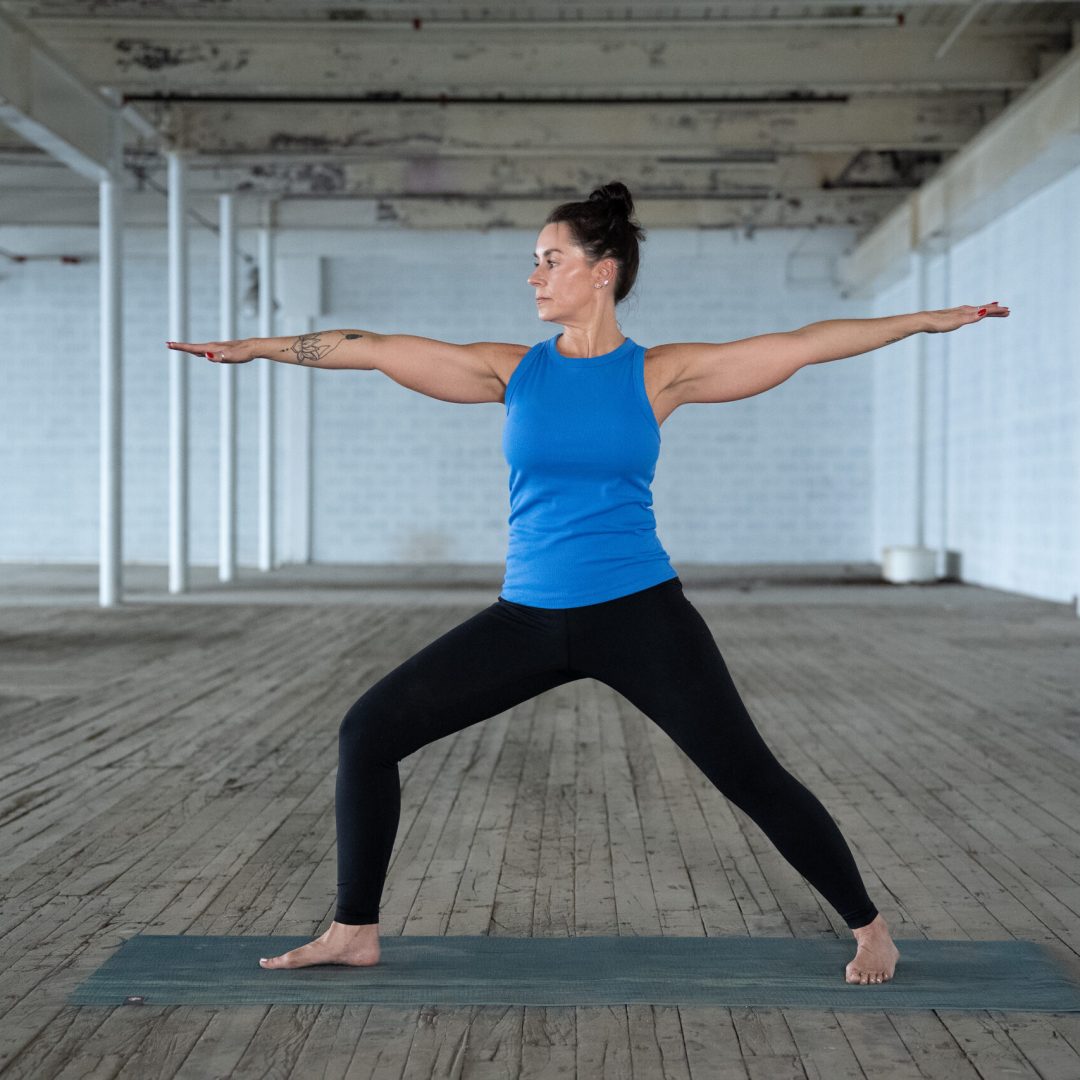 Yoga teacher jane does a warrior pose in a warehouse space in greenville sc