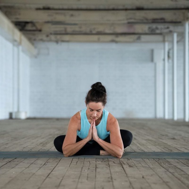 Yoga instructor Jane bows down in prayer pose on her mat utilizing her mindful breath skills in Greenville SC
